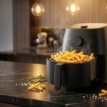 Air fryer sobre bancada de cozinha com batatas crocantes